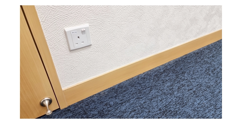 Textured wallpaper with an electrical outlet and baseboard